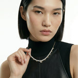 Woman wearing 14k yellow gold Unbound 10 necklace with graduated round lab-grown diamonds, styled with a black turtleneck for a modern layered look
