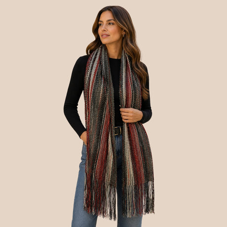 Front view of model wearing You & Eye deep burgundy and charcoal chevron knit scarf with fringe trim styled over a black top and jeans