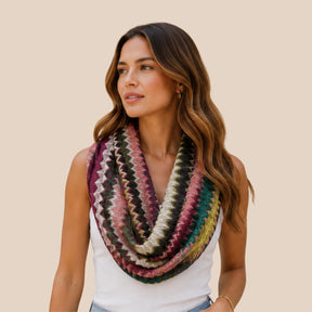 Front view of model wearing You & Eye colorful jewel-tone chevron open-knit snood infinity scarf draped over a white tank top