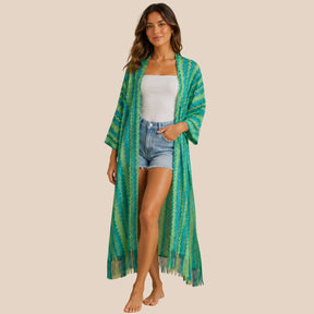 Front view of model wearing You & Eye green lagoon chevron knit long kimono with fringe hem over denim shorts and white top