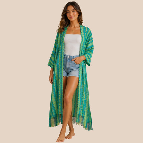 Front view of model wearing You & Eye green lagoon chevron knit long kimono with fringe hem over denim shorts and white top