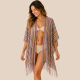 Front view of model wearing You & Eye rainbow fringe crochet short poncho with unstitched sides over a beige two-piece swimsuit