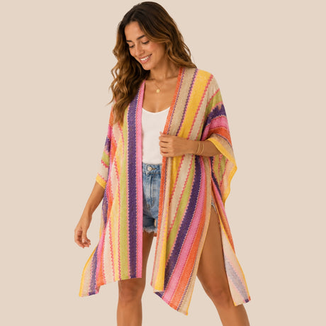 Front view of model wearing You & Eye sunset chevron knit poncho with unstitched open sides over denim shorts and white top